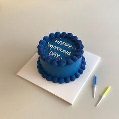 a blue birthday cake sitting on top of a table next to a marker and pen