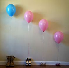 four balloons are hanging on the wall near shoes and high heeled shoes in front of them