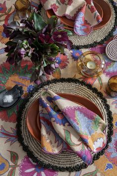 a table topped with plates covered in cloths and place settings next to a potted plant