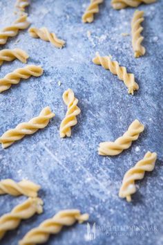 some pasta is being made on a blue surface with the word's spelled out in cursive writing