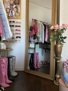 a mirror sitting on top of a wooden floor next to a vase filled with flowers