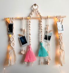 several pictures hanging on a wall with string lights and tassels attached to them