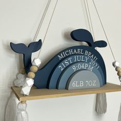 a blue whale hanging from the side of a wooden shelf with tassels on it