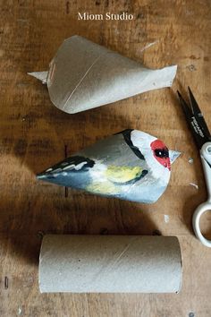 a bird is sitting on top of toilet paper next to scissors and a roll of toilet paper