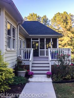 a house with steps leading up to the front door and flowers in pots on the porch