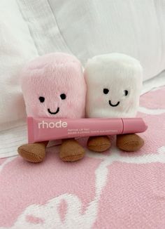 two toothbrushes sitting next to each other on top of a pink bed sheet