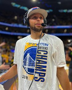 a man with headphones on standing in front of a crowd at a basketball game