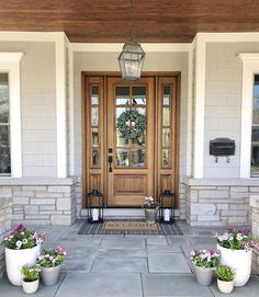 two planters on the front steps of a house with flowers in them and a lantern hanging from the ceiling