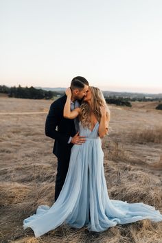 a man and woman are kissing in the middle of an open field with tall grass