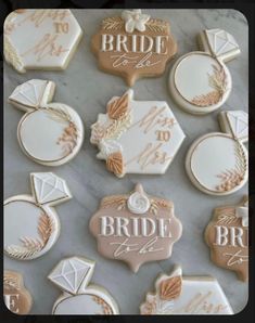 wedding cookies decorated with royal icing and handwritten names are displayed on a marble surface