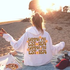 a woman sitting on the beach eating pizza