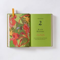 an open book with the number two on it's cover and floral design in green