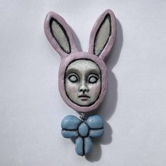 a close up of a small rabbit head brooch on a white surface with blue beads