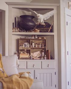 a white bird is perched on top of a book shelf in the corner of a living room