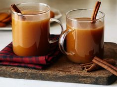 two mugs filled with cinnamon sitting on top of a cutting board