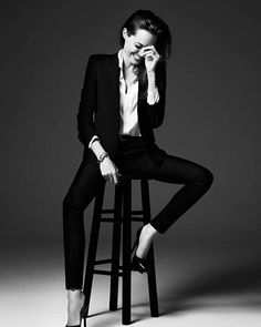 a woman sitting on top of a stool wearing black pants and heels with her legs crossed