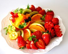 a white plate topped with sliced fruit and oranges