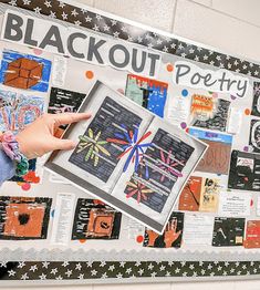 a person holding up a book in front of a bulletin board