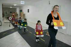 a group of people walking down a hallway with cars on the floor and one woman holding a cardboard cutout