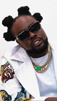 a man wearing sunglasses and a white jacket with two braids on his head, sitting down