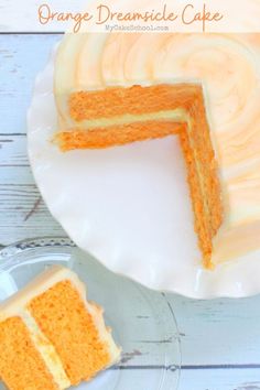 an orange cake with white frosting on a plate next to a slice cut out