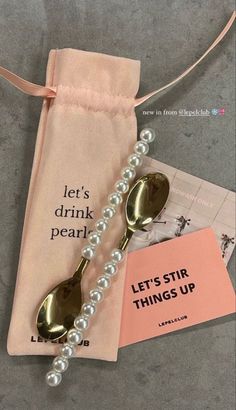 a pair of spoons sitting on top of a pink bag next to a card