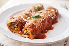 two enchiladas on a plate with sauce and cheese