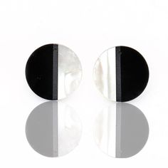 two round black and white earrings sitting next to each other