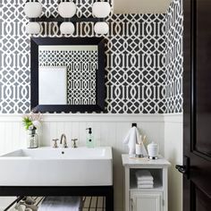 a white sink sitting under a bathroom mirror next to a black and white tiled wall