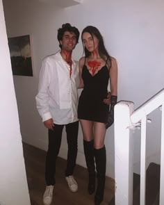 a man and woman dressed in costumes standing next to each other on the stairs with blood all over their body