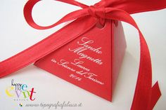 a close up of a red triangle shaped gift box with a ribbon tied around it