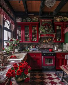 a kitchen with red cabinets and checkered flooring on the walls, potted plants in front of the stove