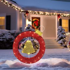 a christmas wreath and ornament in front of a house decorated for the holidays