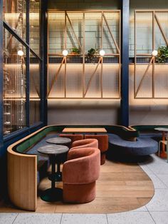 the inside of a restaurant with tables and chairs in front of large windows that are lit by lamps