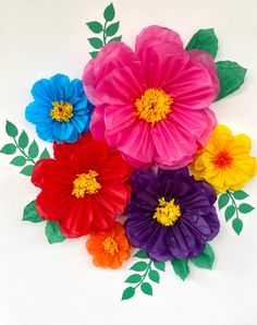 colorful paper flowers on white background with green leaves