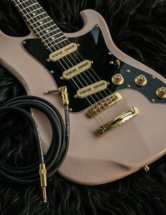 an electric guitar laying on top of a black furry surface