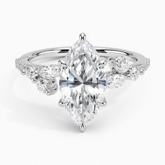 an engagement ring with a pear shaped diamond on the side and pave set shoulders