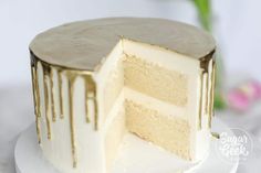 a cake with white frosting and dripping icing on it's side, sitting on a plate