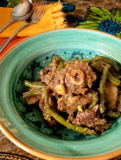 a blue bowl filled with meat and green beans