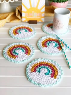 four crocheted coasters on a table next to a coffee cup and straw