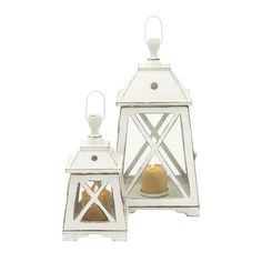 two white lanterns with one lit candle and the other on top of eachother