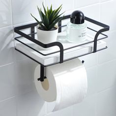 a black metal shelf holding two rolls of toilet paper and a potted plant