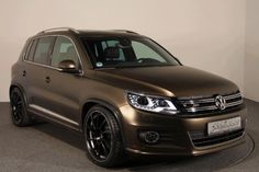 a brown volkswagen tigua parked in a room with black flooring and white walls