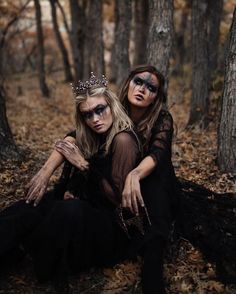 two women dressed in black sitting on the ground with their faces painted to look like they are