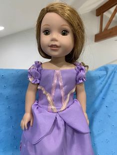 the doll is wearing a purple dress with gold trimmings on it's chest