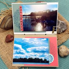 an open book with pictures on it sitting next to some rocks and other things in the background