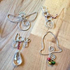 three pieces of metal wire sitting on top of a wooden table next to beads and scissors