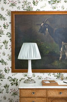 a painting hangs on the wall next to a lamp