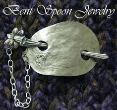 a close up of a metal object on a knitted surface with the words bent spoon jewelry written above it