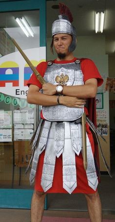 a man dressed as a roman soldier standing in front of a store window with his arms crossed